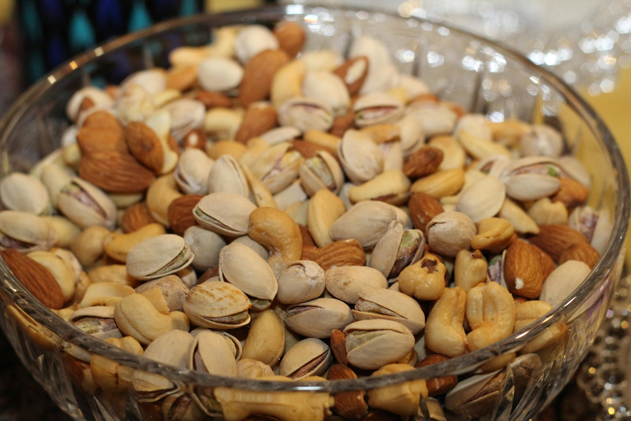 Services A close-up view of a glass bowl filled with various mixed nuts, including almonds, cashews, and pistachios.